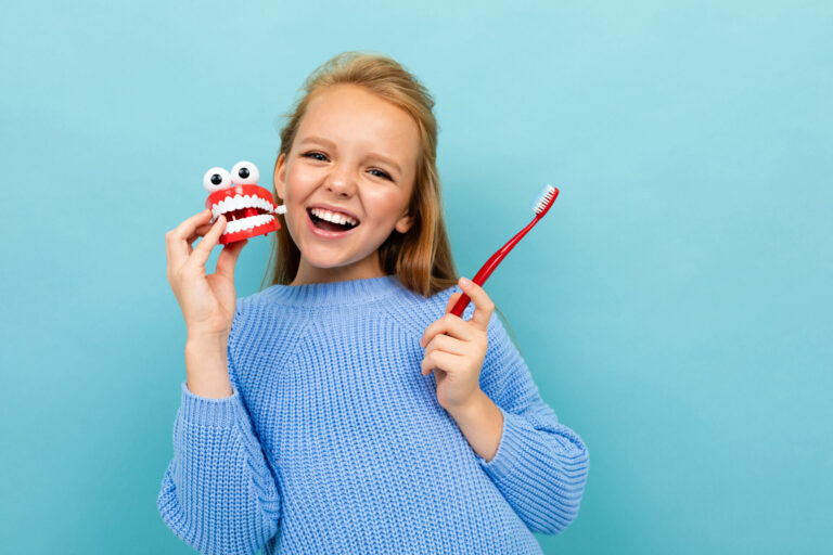 beautiful happy girl laughs on a blue background with a toothbrush, toothpaste concept